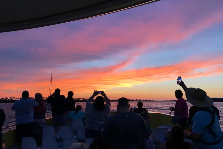 a group of people on a boat at sunset